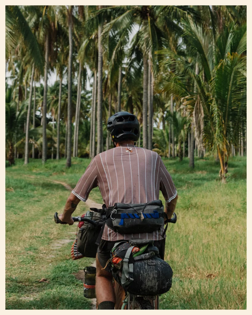 Bikepacker roulant dans une cocoteraie sur la Trans-Salvador, au Salvador