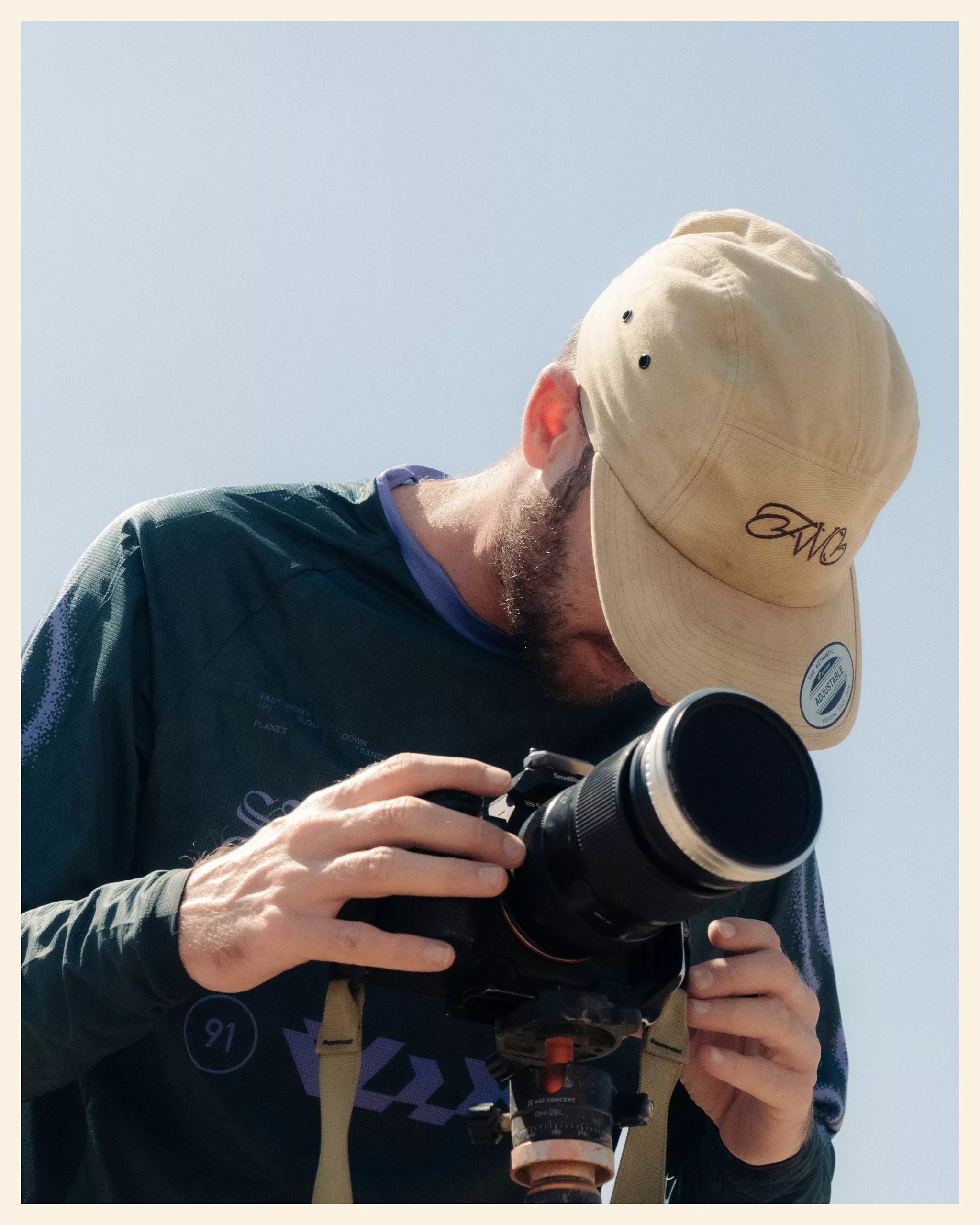Photographe en maillot et casquette Fast Won't Last réglant son appareil photo